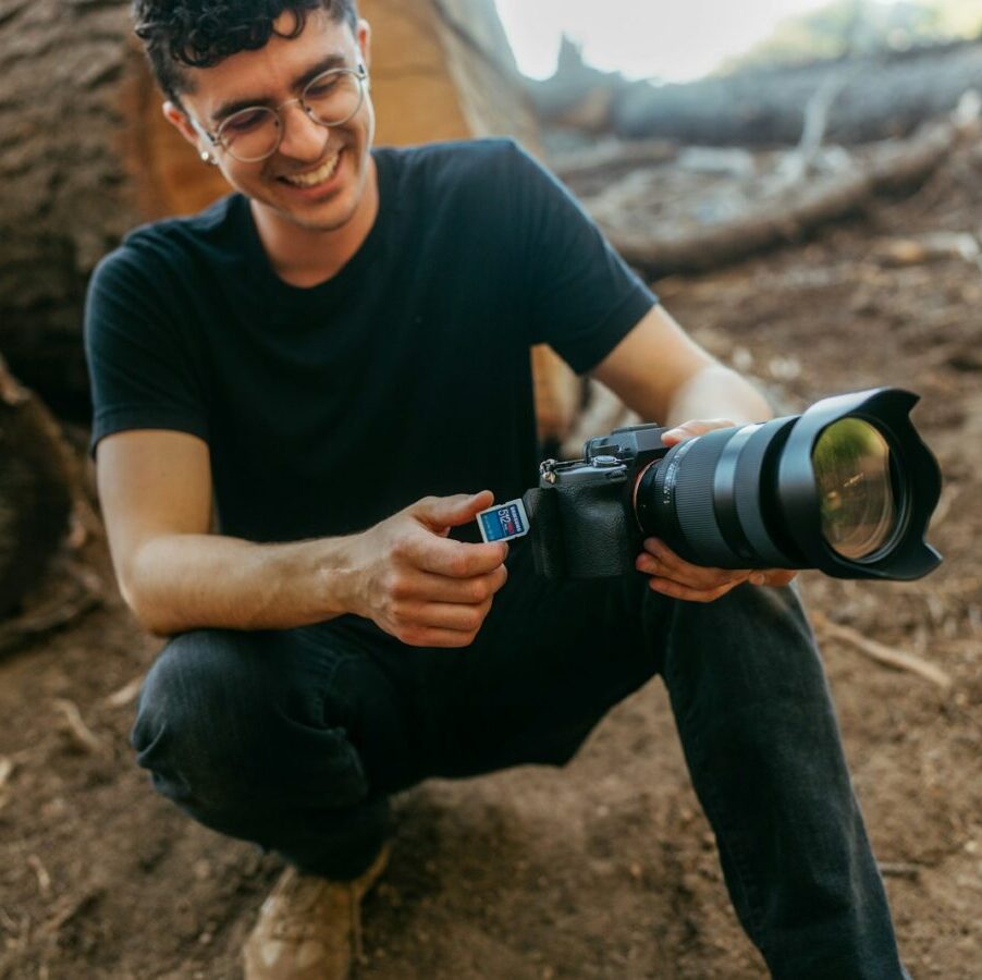 Man with camera in forest with logs